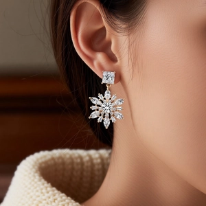 Close-up of 14k gold plated snowflake drop earrings with cubic zirconia on model ear