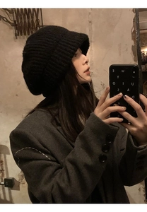 Detail of chunky knit black beret beanie paired with a gray oversized wool coat