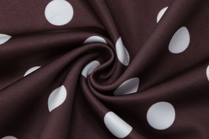 Détail du tissu à pois marron foncé montrant une texture douce et un drapé fluide en spirale