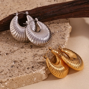 Macro detail of 18K gold and silver plated hoop earrings with textured ripple design