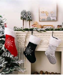 Détail de chaussettes de Noël en velours brodé disposées sur une cheminée chaleureuse