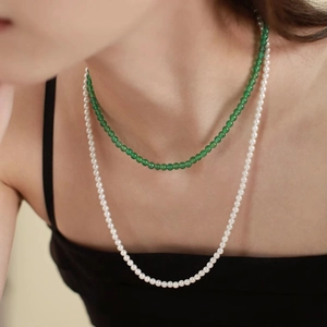 Detail of layered green agate beads and white pearls necklace worn by a fashion model