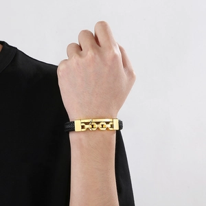 Close-up of black braided leather bracelet with golden buckle worn on male wrist