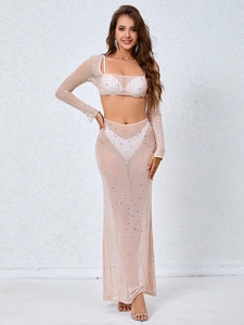 Detail of sheer mesh fabric with shimmering rhinestones on a beige long sleeve crop top