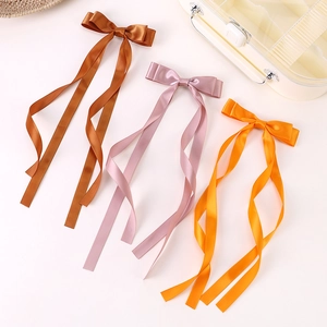 Close-up of triple satin ribbon hair bows in brown, pink, and yellow with long streamers