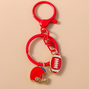Macro detail of red rugby ball and helmet keychain charms with elegant gold metal trim