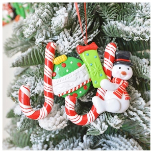 Detail of JOY polymer clay ornament with snowman on a snowy Christmas tree branch