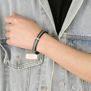 Men's punk leather bracelet with stainless steel chain on wrist over denim jacket