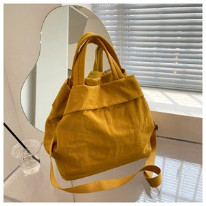 Detail of yellow nylon tote bag with pleated texture and adjustable shoulder strap