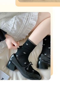 Detail of black mid-calf socks with white bow pattern and wavy edge in Mary Jane shoes