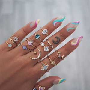Detailed close-up of bohemian gold rings with colorful opal and zircon on fingers