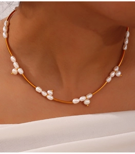 Detail of gold choker necklace with irregular freshwater pearls worn on a female neck