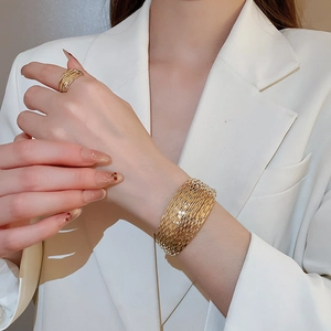 Detail of gold multilayer textured cuff bracelet and matching ring set on model