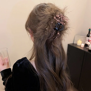 Macro detail of the brown feather hair claw clip with glass beads worn on model hair