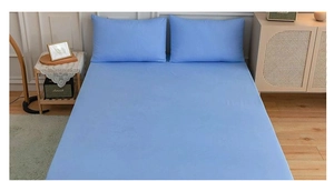 Detail of light blue solid color bedding set featuring one fitted sheet and two pillowcases