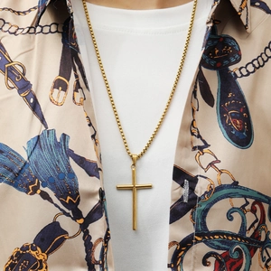 Close-up of gold stainless steel cross pendant necklace worn by male model on vintage shirt