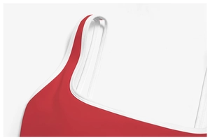 Detail of red yoga sports bra featuring wide straps and contrasting white piped edges