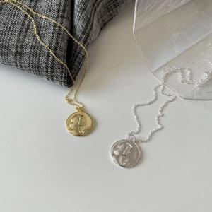 Detailed view of gold and silver 925 sterling silver coin necklaces with embossed pendants