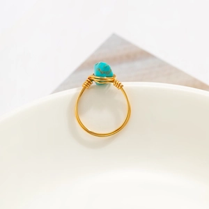 Detail of handmade gold wire-wrapped ring with irregular turquoise stone in ethnic style