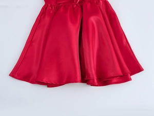 Détail de mini robe rouge en satin avec ourlet plissé et tissu brillant sur fond blanc