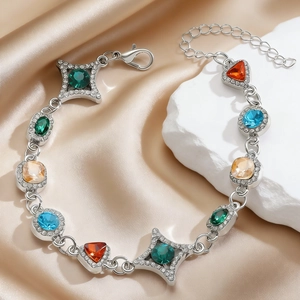 Detail eines silbernen Armbands mit bunten Edelsteinen auf champagnerfarbener Seide