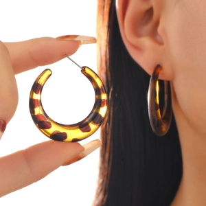 Detailed view of amber leopard print C-shape acrylic earrings with tortoiseshell texture