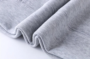 Macro detail of light grey knitted fabric showing premium texture of fleece tracksuit