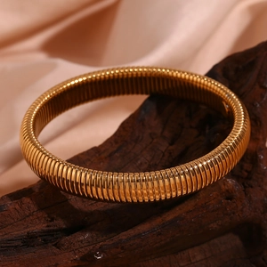 Détail du bracelet flexible tubogas de 10mm plaqué or 18K sur un support en bois élégant