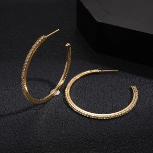 Macro shot of gold-plated geometric C-hoop earrings with shimmering pave-set zirconia