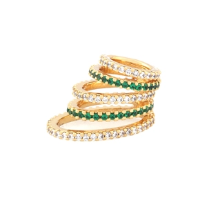 Close-up of five stacked gold rings with emerald green and white zircon gemstones