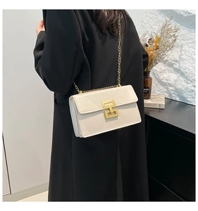 Detail of cream leather crossbody bag with gold square buckle and chain strap on model
