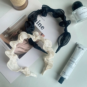 Close-up of black and white ruffled mesh headbands styled with lifestyle accessories