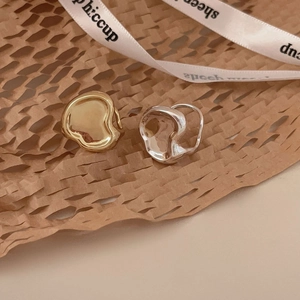 Irregular textured gold and silver lava style stud earrings on a textured paper background