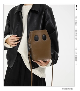 Brown coffin-shaped shoulder bag featuring black oval accents and metal zipper detail