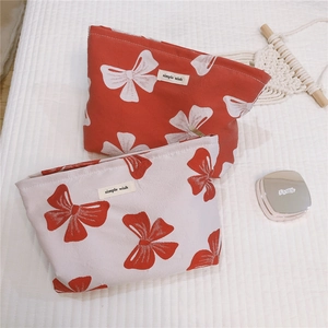 Macro view of canvas makeup bags featuring red bow patterns and zippered closure detail