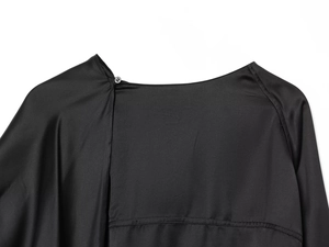 Detail of elegant black satin collar featuring a refined round button on the neckline