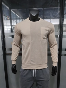 Detail of beige crewneck sweatshirt featuring corduroy patchwork and a chest pocket