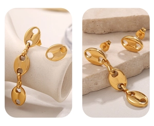 Macro shot of asymmetric gold-tone pig nose anchor chain earrings with tassel detail