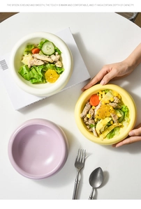 Close-up of three ceramic salad bowls in cream, yellow, and purple with stainless cutlery