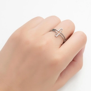 Minimalist stainless steel open ring with cutout cross design worn on middle finger