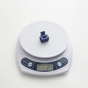 Detail view of a 2.7g matte blue square hair claw clip on a digital scale for weight display