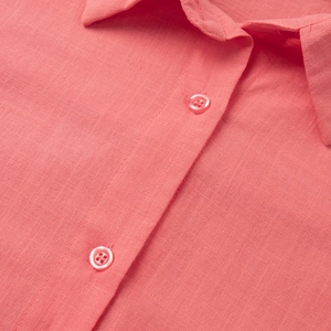 Detail of coral cotton fabric texture and matching resin buttons on shirt collar
