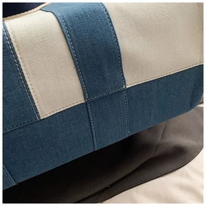 Detail showing high-quality denim texture and white contrast stitching on a patchwork tote