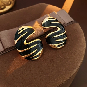 Vintage gold and black enamel C-shaped wave earrings on a brown velvet gift box