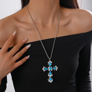 Close-up of cross pendant necklace with blue drop stone and sparkling white crystals