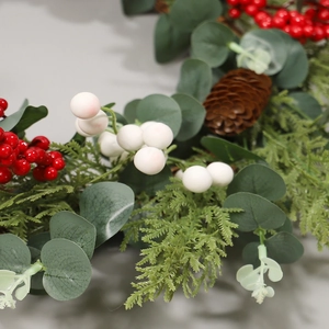 Christmas wreath with red berries, pine cones and eucalyptus leaves on grey background