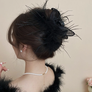 Detail shot of elegant black feather hair claw clip on model with pearls