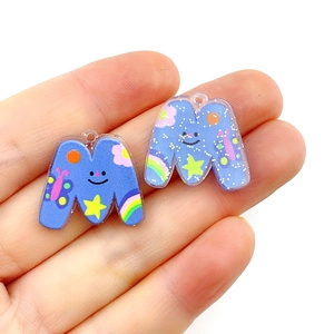 Close-up of blue acrylic M letter charm with colorful rainbow and star patterns