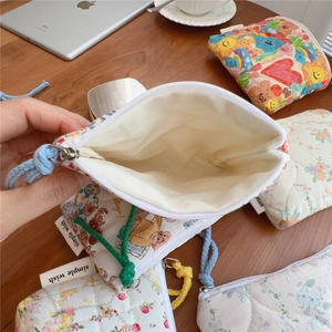 Detailed close-up of quilted floral cotton pouches featuring zippers and brand labels