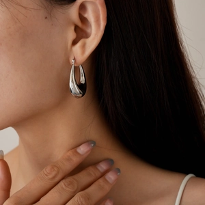 Dettaglio ravvicinato di un orecchino a goccia a forma di U d'argento su modella elegante